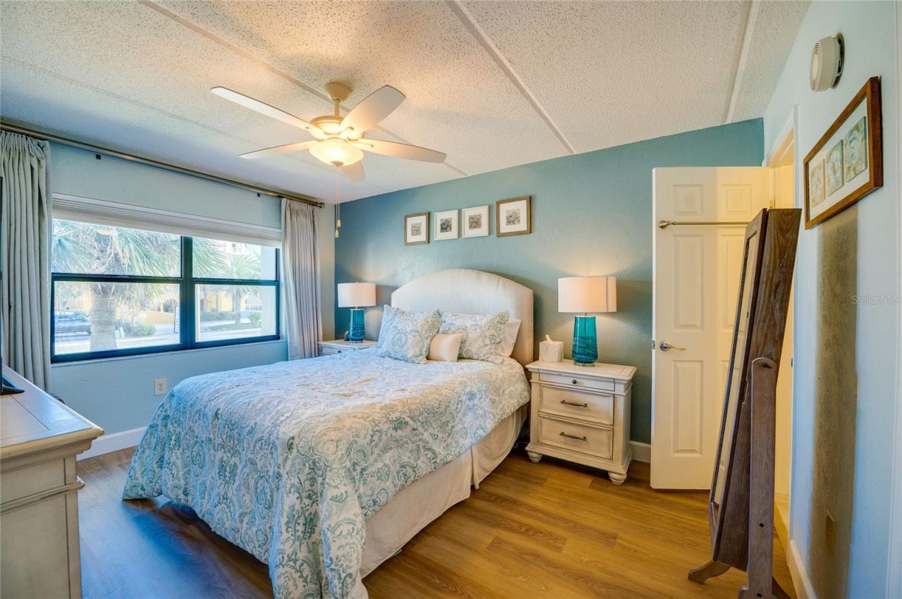 Photo 15 of 20: Relaxing primary bedroom featuring vinyl plank flooring, a ceiling fan, and a large window that fills the room with natural light.
