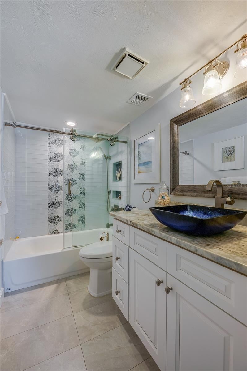 Photo 17 of 20: Updated primary bathroom vanity with a quartz countertop, vessel sink, modern fixtures, and coordinated lighting.