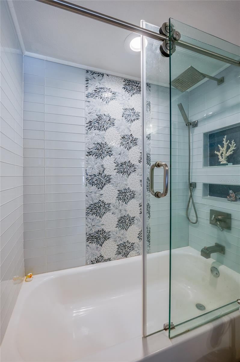 Photo 18 of 20: Tub and shower combination with glass enclosure and decorative tile accents, offering a clean and refreshed design.