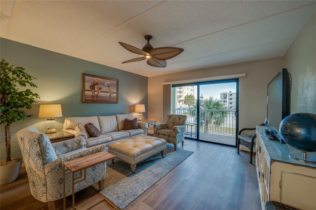 Photo 11 of 20: Inviting living room with vinyl plank flooring, ceiling fan, and sliding glass doors that bring in natural light and provide outdoor access.