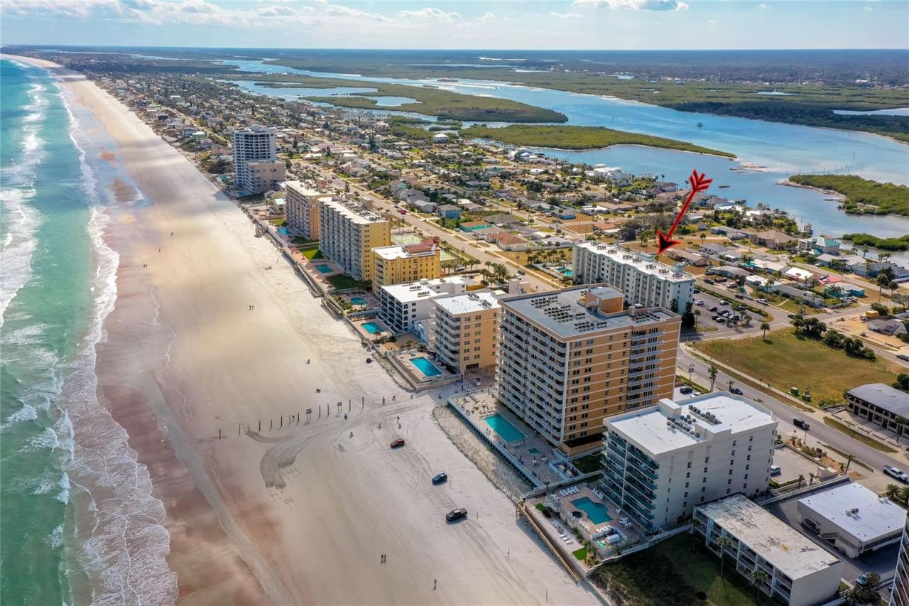 Photo 3 of 20: Sweeping aerial perspective showcasing the beach, neighboring condominiums, and inland water features.