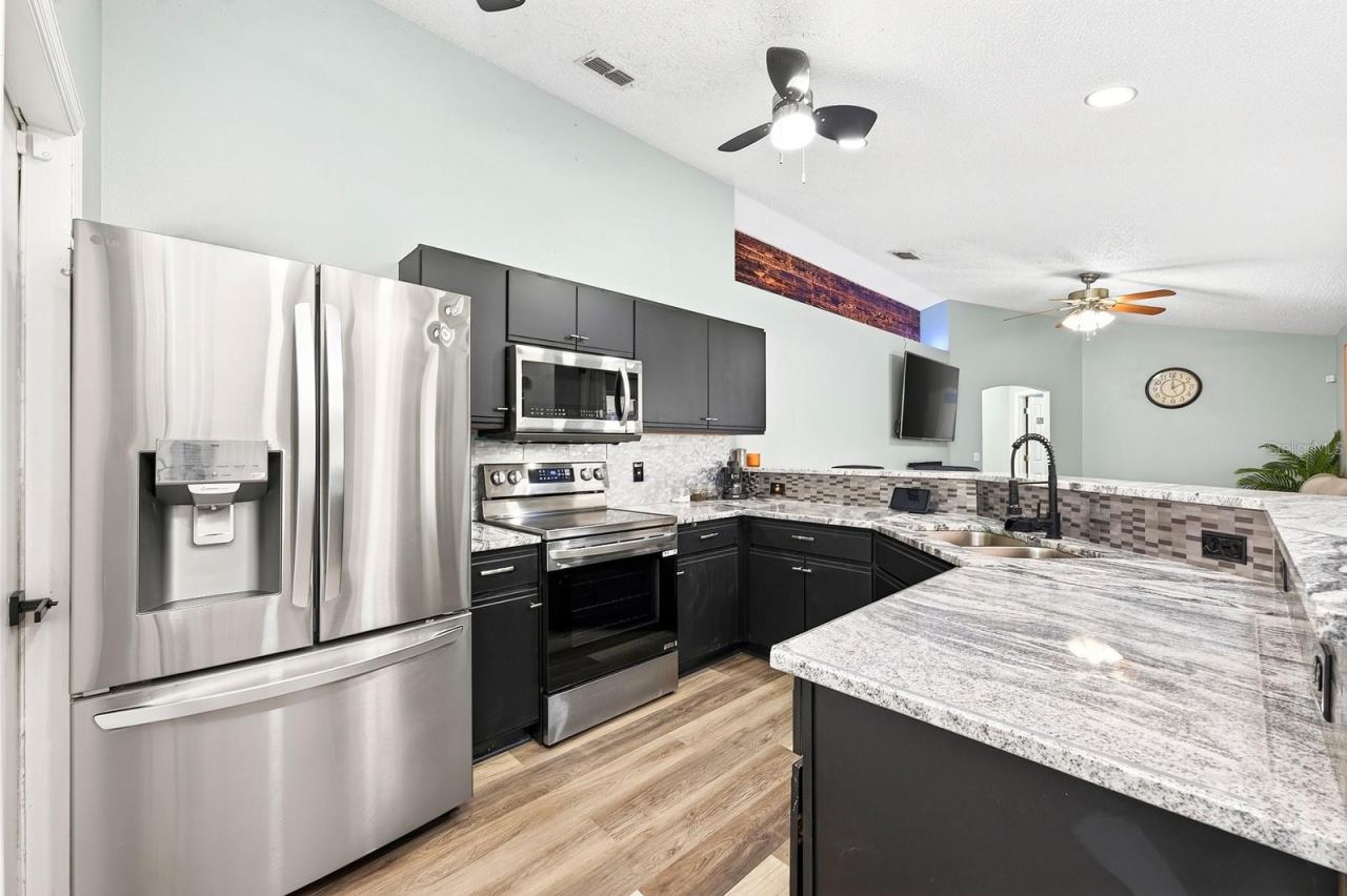 Photo 2 of 20: The open kitchen is ready for everything from busy mornings to entertaining, featuring STAINLESS STEEL APPLIANCES, modern neutral countertops, a decorative backsplash, and two pantries providing exceptional storage.