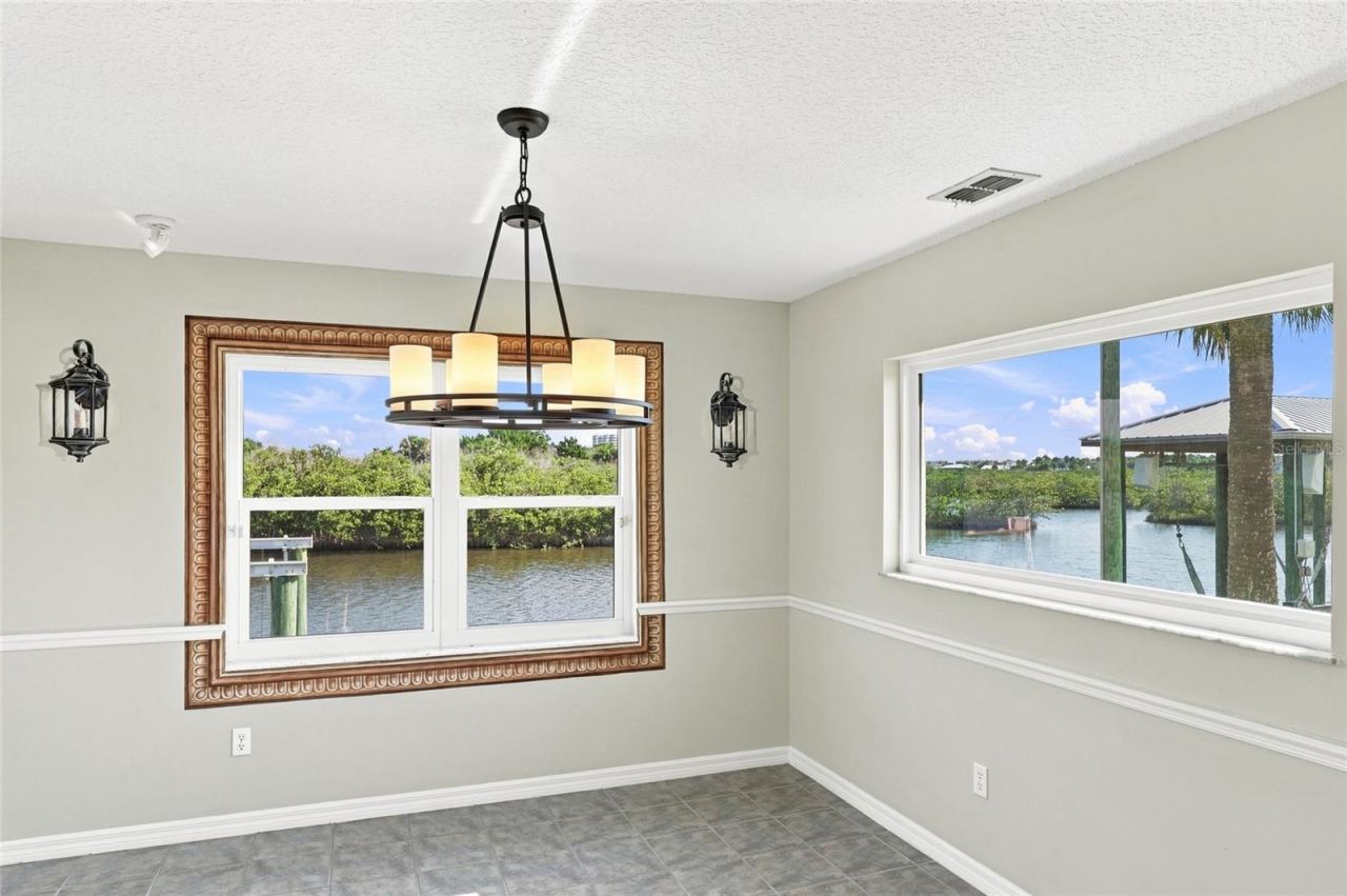 Photo 20 of 20: reakfast nook — Breakfast nook with picture-frame window overlooking the canal and a second window framing a palm tree and neighboring dock.