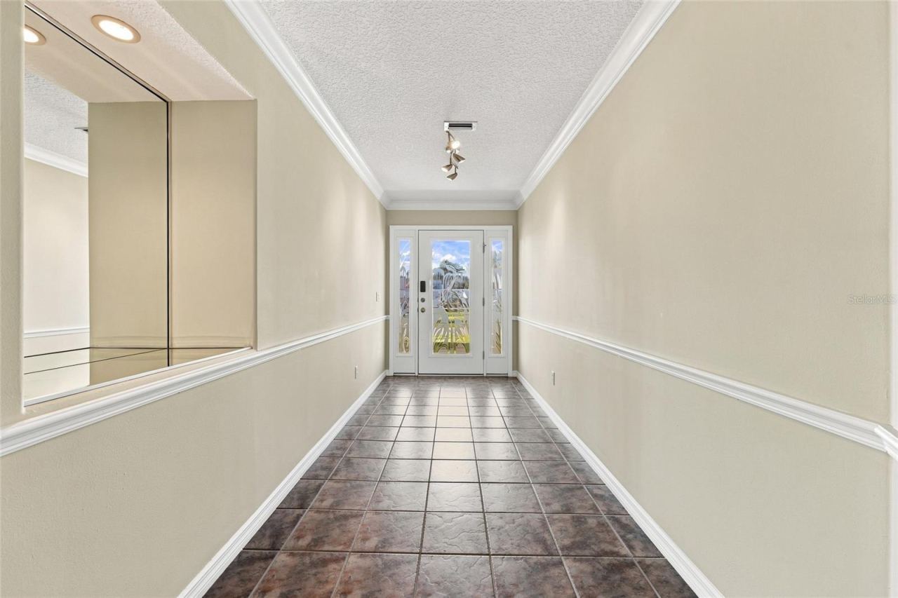 Photo 6 of 20: Entry hallway — Tiled entry hallway with crown molding, chair rail, and a glass-paneled front door with sidelights.
