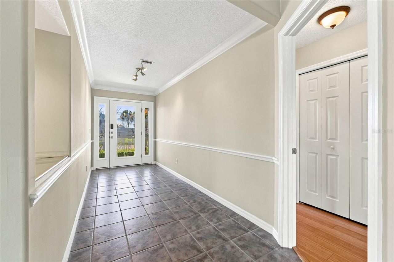 Photo 9 of 20: Entry foyer — Foyer with tile flooring, crown molding, and double closet doors, opening into the main living area.