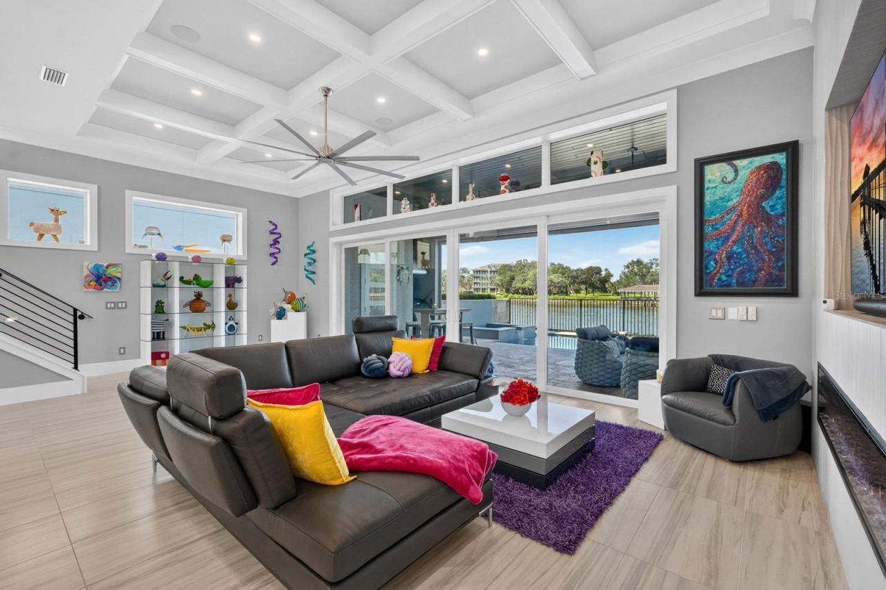 Photo 6 of 20: Main-level gathering space with a sleek electric fireplace, integrated entertainment wall and direct connection to the covered outdoor living, pool and Intracoastal.