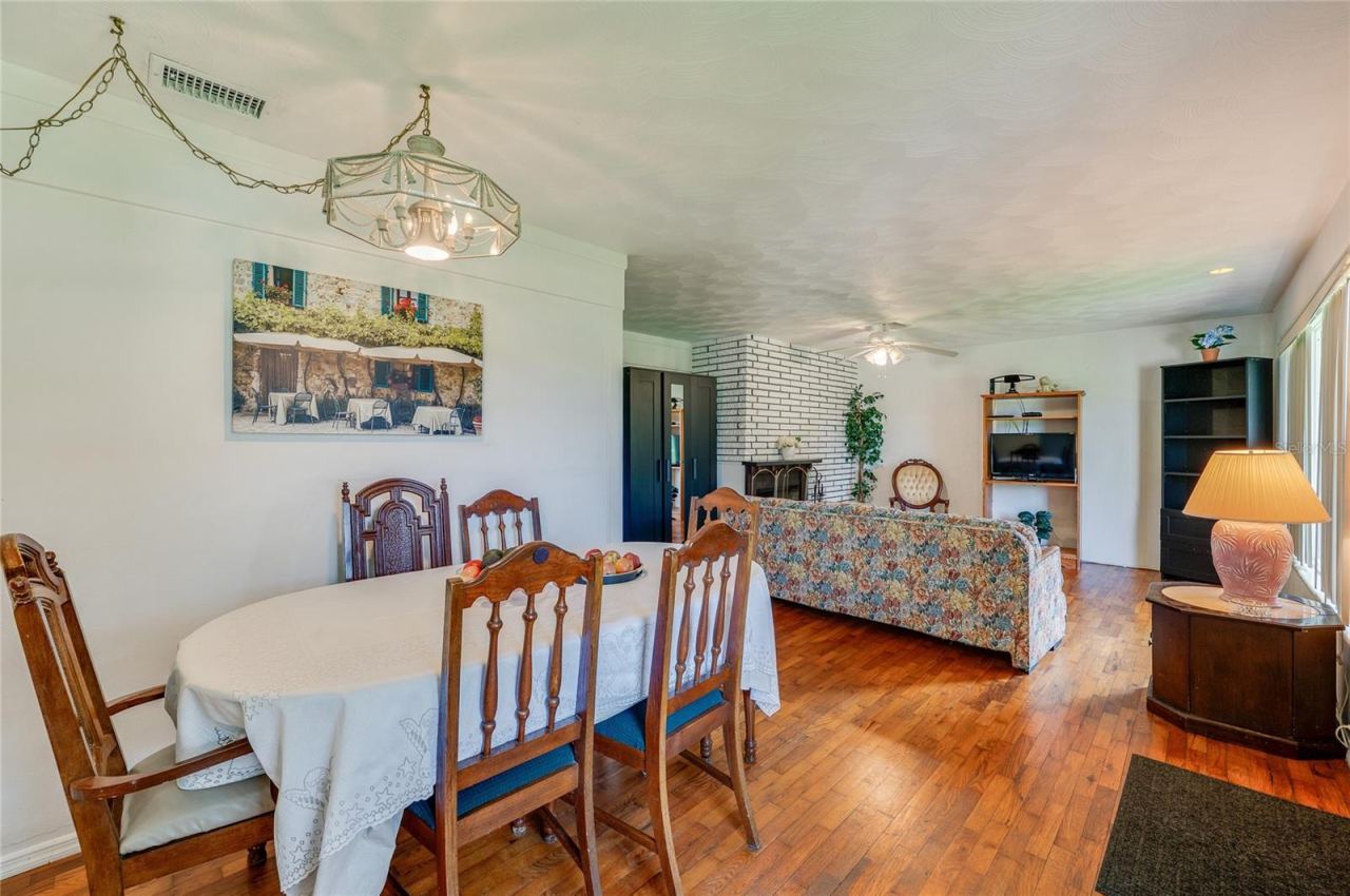 Photo 9 of 20: Expansive living and dining area highlighted by continuous hardwood flooring, clean neutral walls, and a hanging light fixture. The flexible open floor plan offers a bright atmosphere with smooth visual transitions.