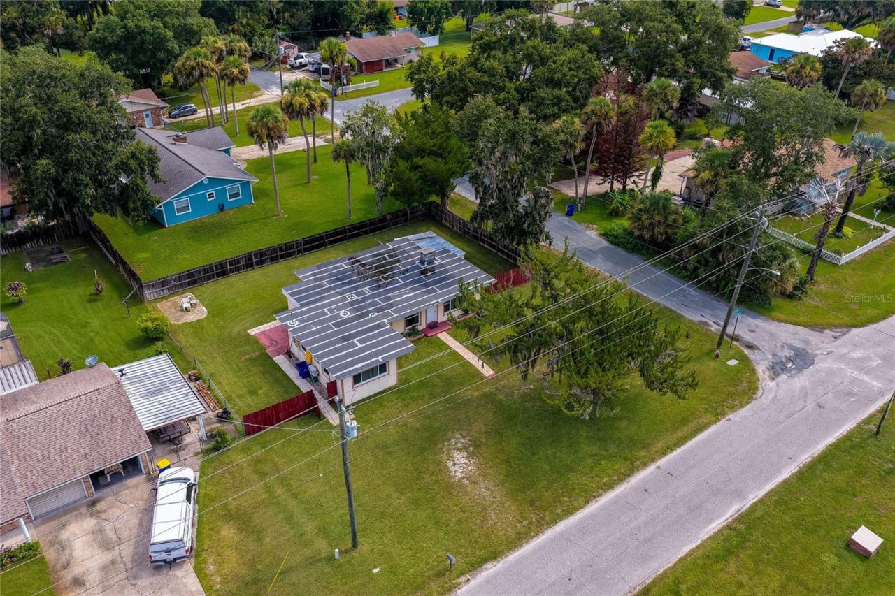 Photo 3 of 20: Elevated aerial view of the home and surrounding residential neighborhood showing a corner lot layout, and lush greenery.