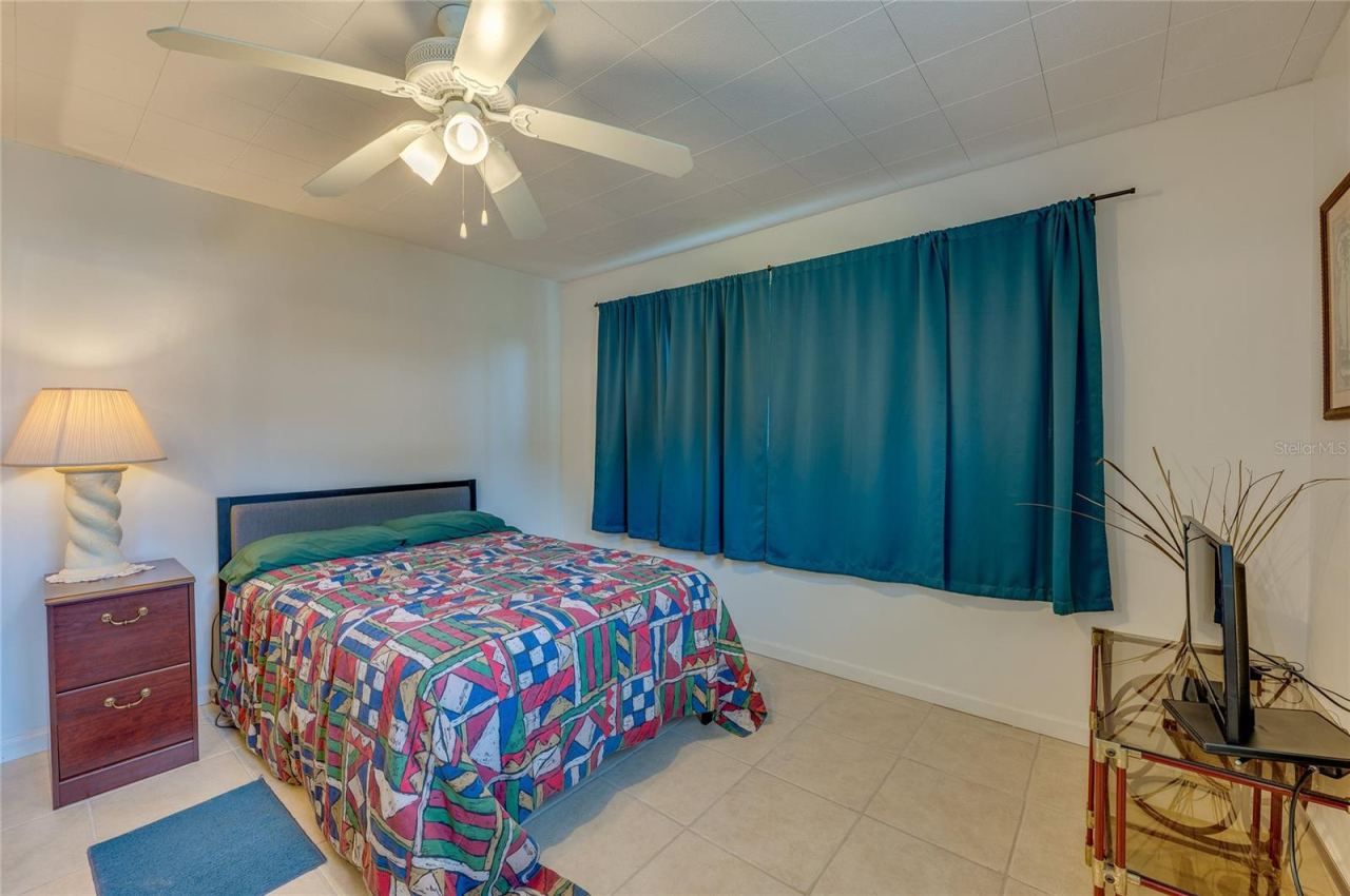 Photo 14 of 20: In-Law suite with it’s own outside entrance featuring neutral tile flooring, an overhead ceiling fan, and a large window accented by full-length teal drapes.