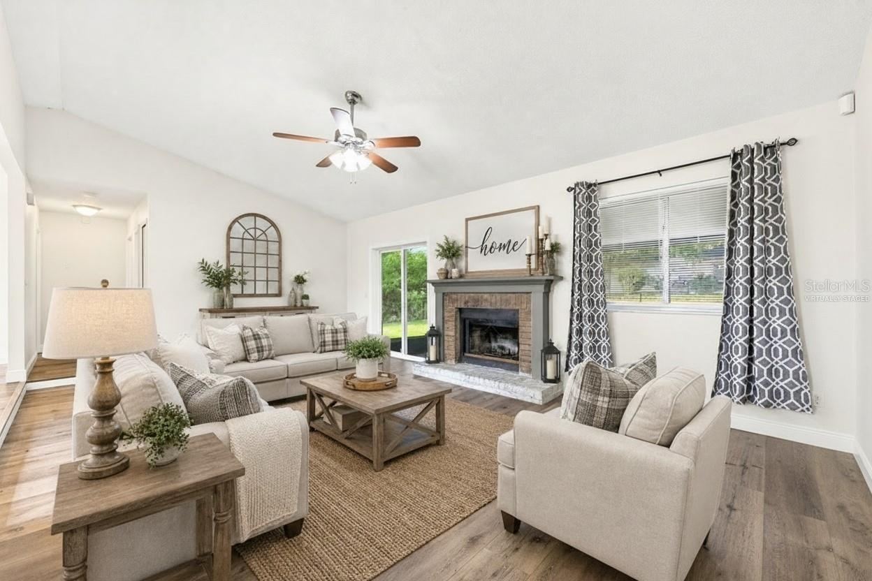 Photo 3 of 20: Step inside to discover a bright and inviting Living Room filled with NATURAL LIGHT and centered around a cozy WOOD-BURNING FIREPLACE, creating the perfect gathering space. Virtually Staged