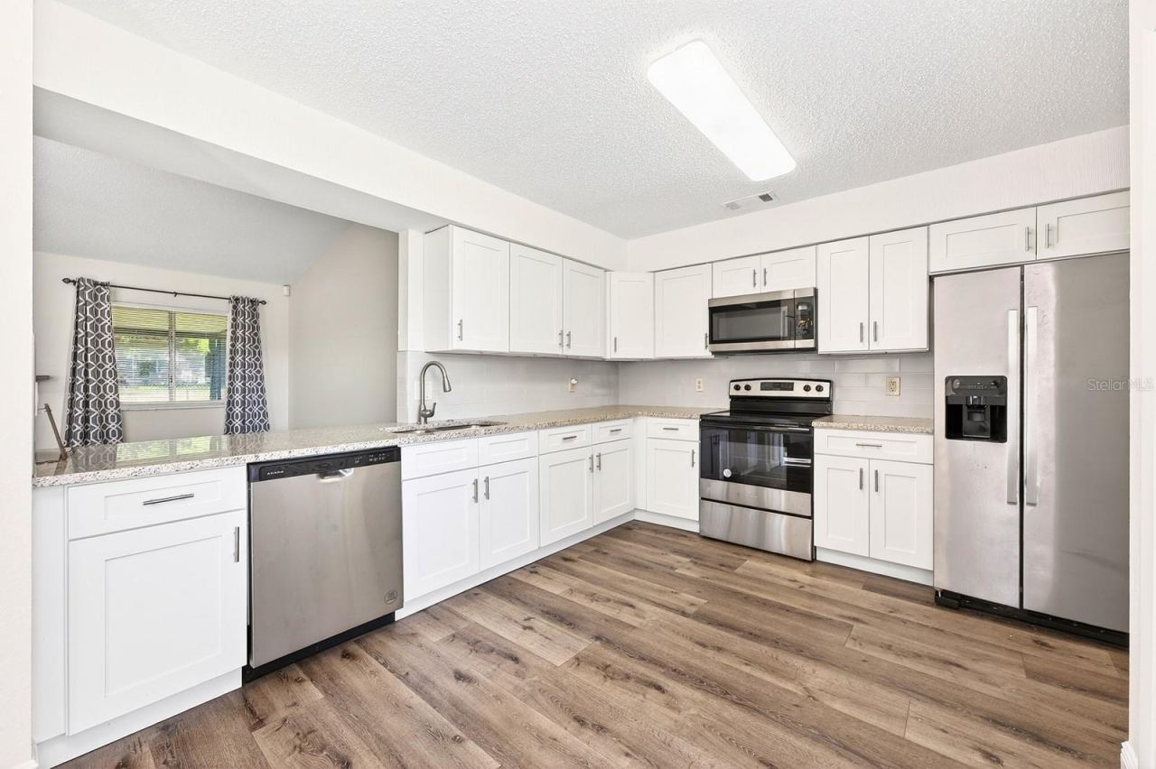 Photo 7 of 20: The UPDATED KITCHEN combines style and functionality with white cabinetry, NEW GRANITE COUNTERTOPS, stainless steel appliances (2023), a closet pantry, and breakfast nook.