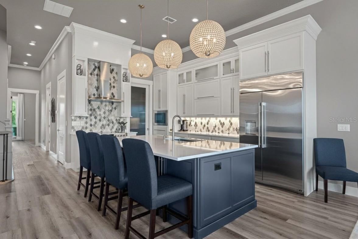 Photo 4 of 20: Stunning designer kitchen featuring custom cabinetry, dramatic statement lighting, and an oversized island that naturally becomes the heart of the home.