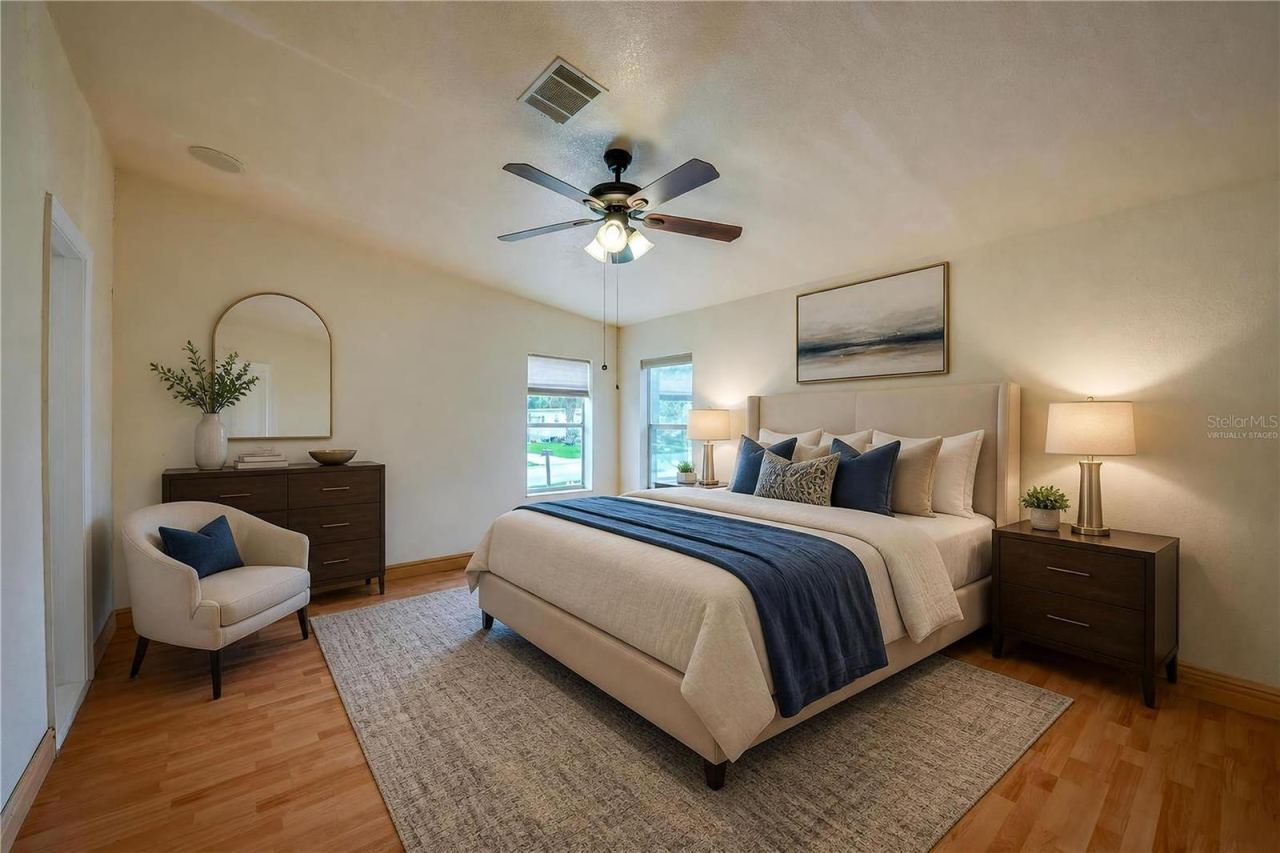 Photo 16 of 20: Virtually Staged...Generously sized primary bedroom with a ceiling fan, multiple windows for natural light, and ample wall space for a variety of furniture arrangements.