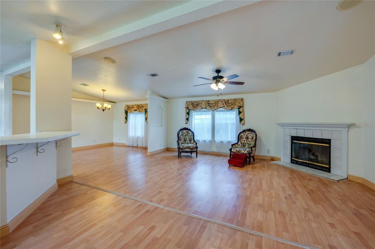 Photo 4 of 20: Another view highlights the generous living space, large windows, fireplace, and open sightlines into the dining area.