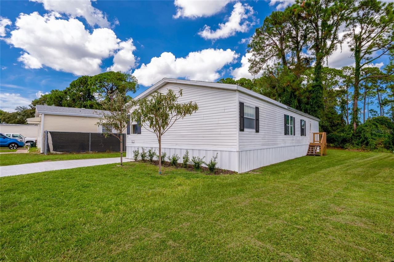 Photo 2 of 20: Well-kept exterior with light siding, contrasting shutters, fresh landscaping, and a spacious lawn surrounding the home.