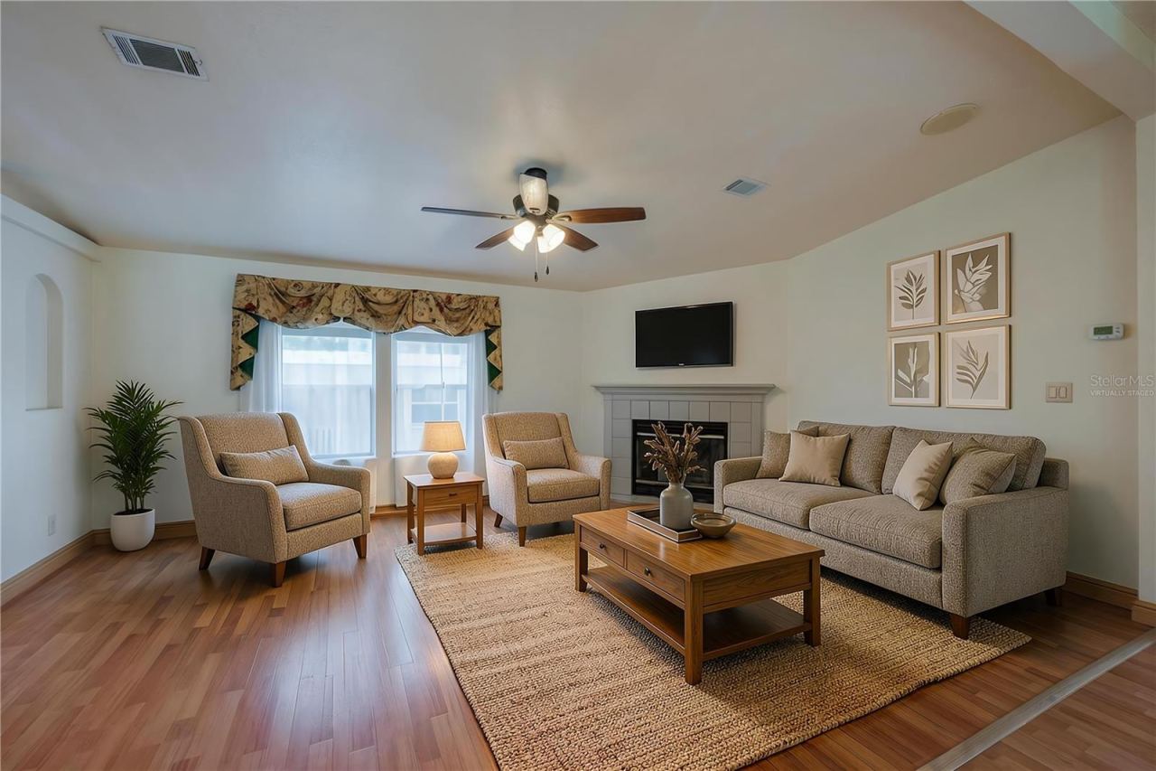 Photo 6 of 20: Virtually Staged...Bright living room offers plenty of flexibility for seating and entertaining, with a fireplace, ceiling fan, and large front-facing windows.