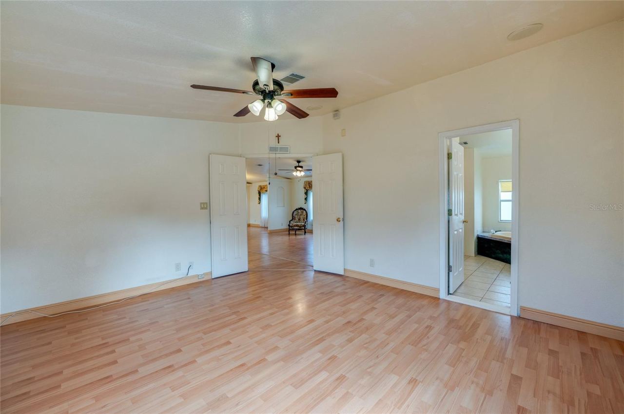 Photo 17 of 20: Spacious primary bedroom features a ceiling fan, double-door entry, and convenient direct access to the adjoining bathroom.