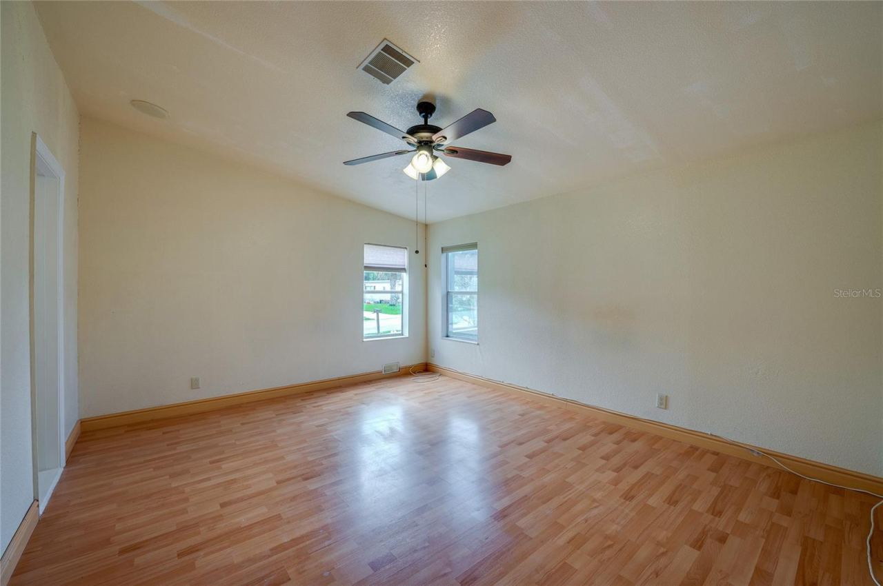 Photo 15 of 20: Generously sized primary bedroom with a ceiling fan, multiple windows for natural light, and ample wall space for a variety of furniture arrangements.