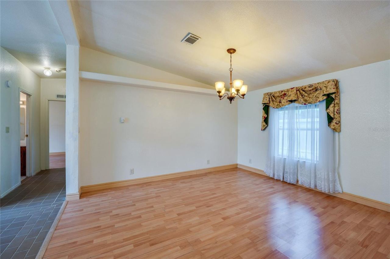 Photo 13 of 20: Defined dining space features a chandelier and a large window for natural light, with an open connection to the surrounding living areas.