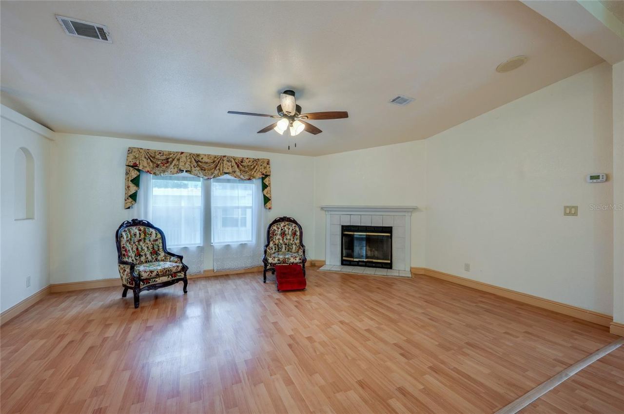 Photo 5 of 20: Bright living room offers plenty of flexibility for seating and entertaining, with a fireplace, ceiling fan, and large front-facing windows.