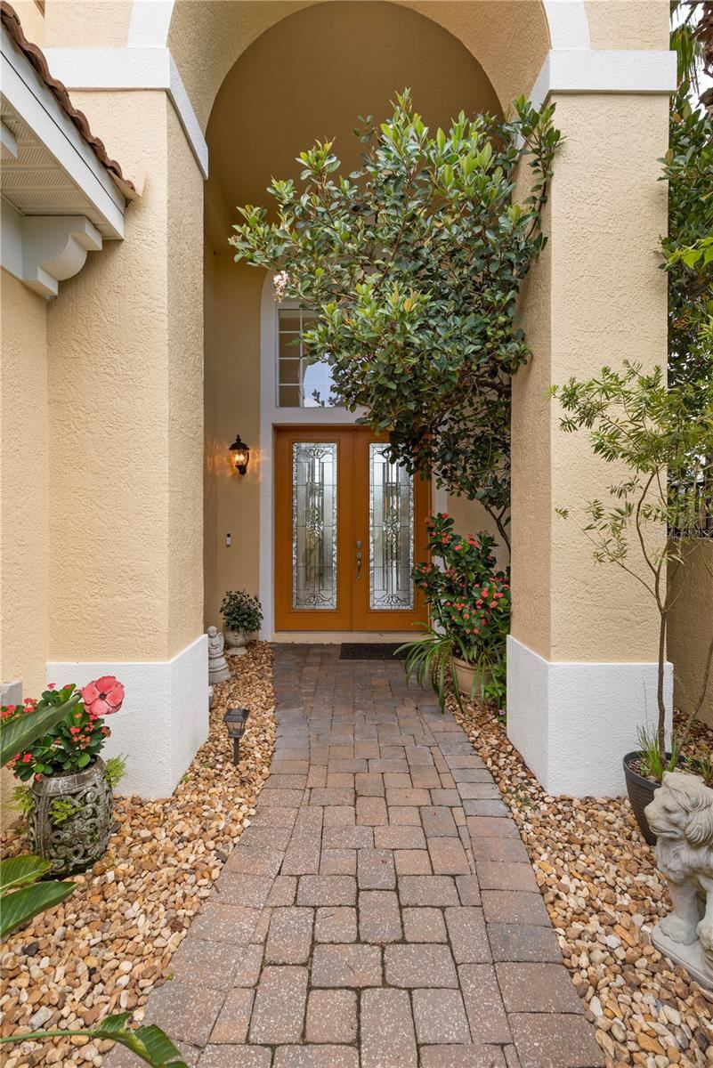 Photo 14 of 20: Lush plantings and bursts of color soften the architecture along the way, making the approach feel less like an entrance and more like a garden passage.