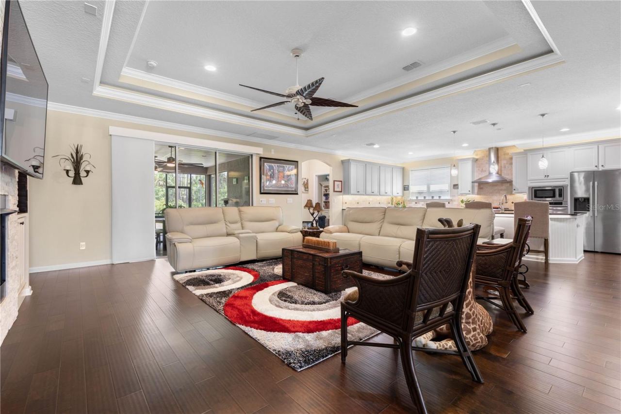 Photo 15 of 20: Settle in and stay awhile—the expansive living room feels warm and inviting, with a dramatic lighted tray ceiling adding character and dimension overhead.