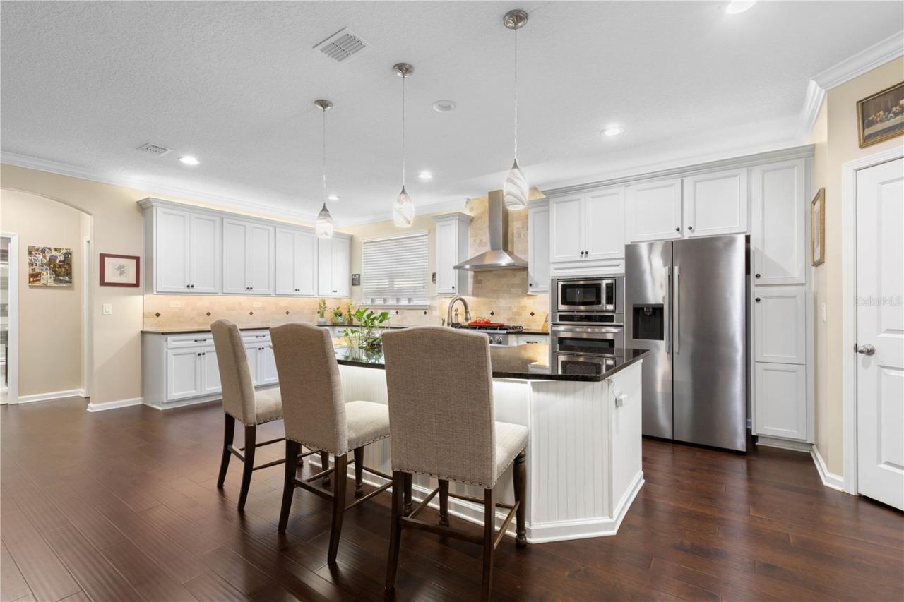 Photo 6 of 20: Made for cooking, conversation, and everything in between—the kitchen pairs a generous island with a beautiful stone-tiled backsplash, crisp cabinetry, and plenty of room to gather.