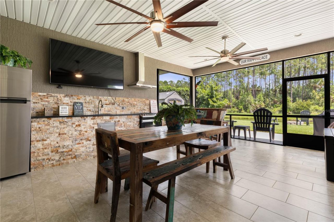 Photo 3 of 20: Perfect for game days and entertaining, this spacious covered outdoor living area features a large TV, full outdoor kitchen, and plenty of seating with serene wooded views.