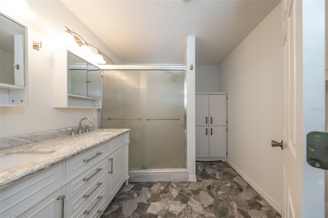 Photo 19 of 20: primary bathroom has been updated, including granite countertops, stone floors and large storage cabinet