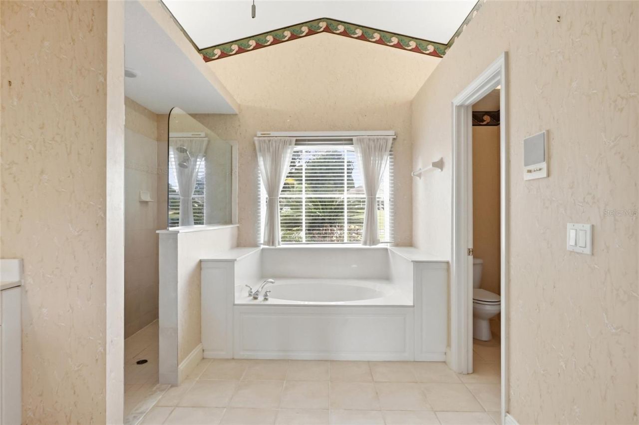Photo 15 of 20: Primary bathroom with a soaking tub beneath a window and a separate shower.