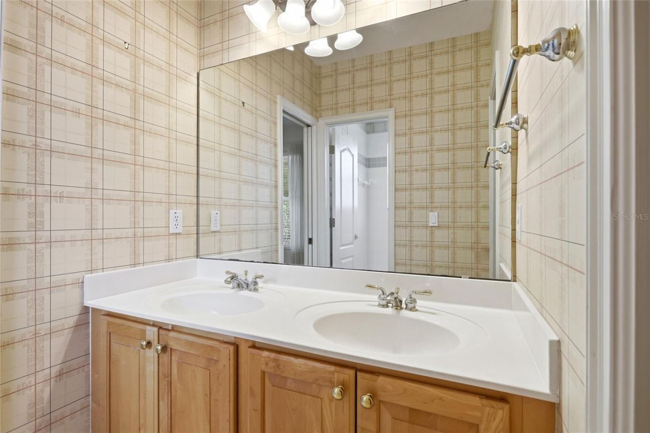 Photo 18 of 20: Jack-and-Jill guest bathroom with a dual-sink vanity, counter space, and cabinet storage,shared by two bedrooms.