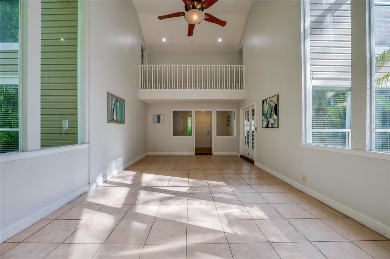 Photo 9 of 20: Expansive two-story living area with high ceilings, large windows, tiled flooring, and a overlook balcony on the upper level.