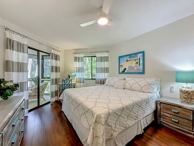 Photo 17 of 20: Primary Bedroom: Engineered Wood flooring - Large window and sliders to Florida Room