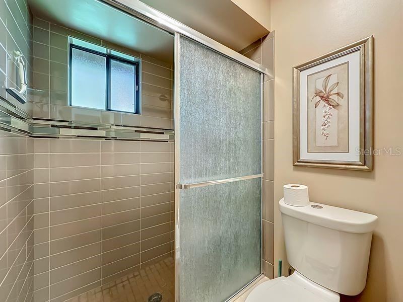 Photo 20 of 20: Primary Bathroom Extended single vanity -full wall mirror-Walk in tile shower-with window and glass enclosure