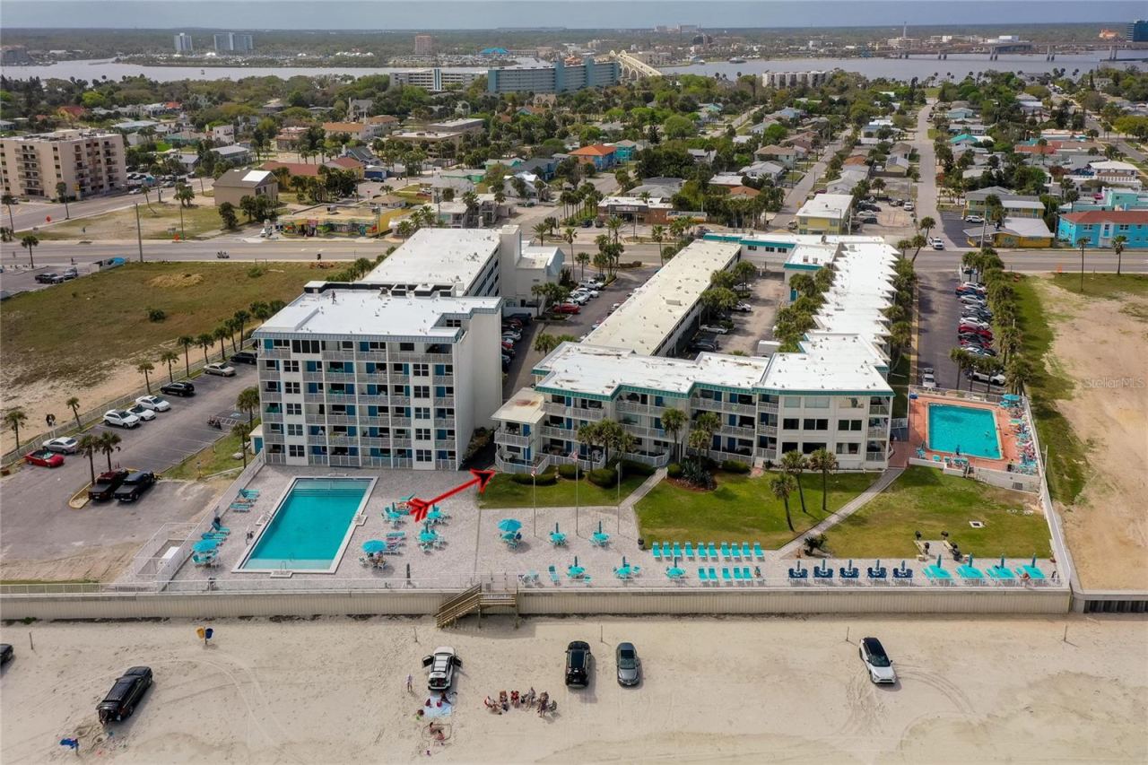 Photo 1 of 20: Expansive aerial of the oceanfront community featuring two pools, sun deck areas, and direct access to the beach. The layout is ideal for enjoying a relaxed coastal lifestyle.