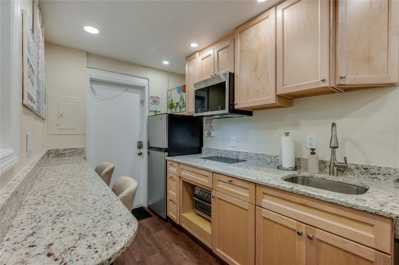 Photo 12 of 20: Efficient kitchen featuring a full-sized refrigerator, sleek cabinetry, and a microwave.
