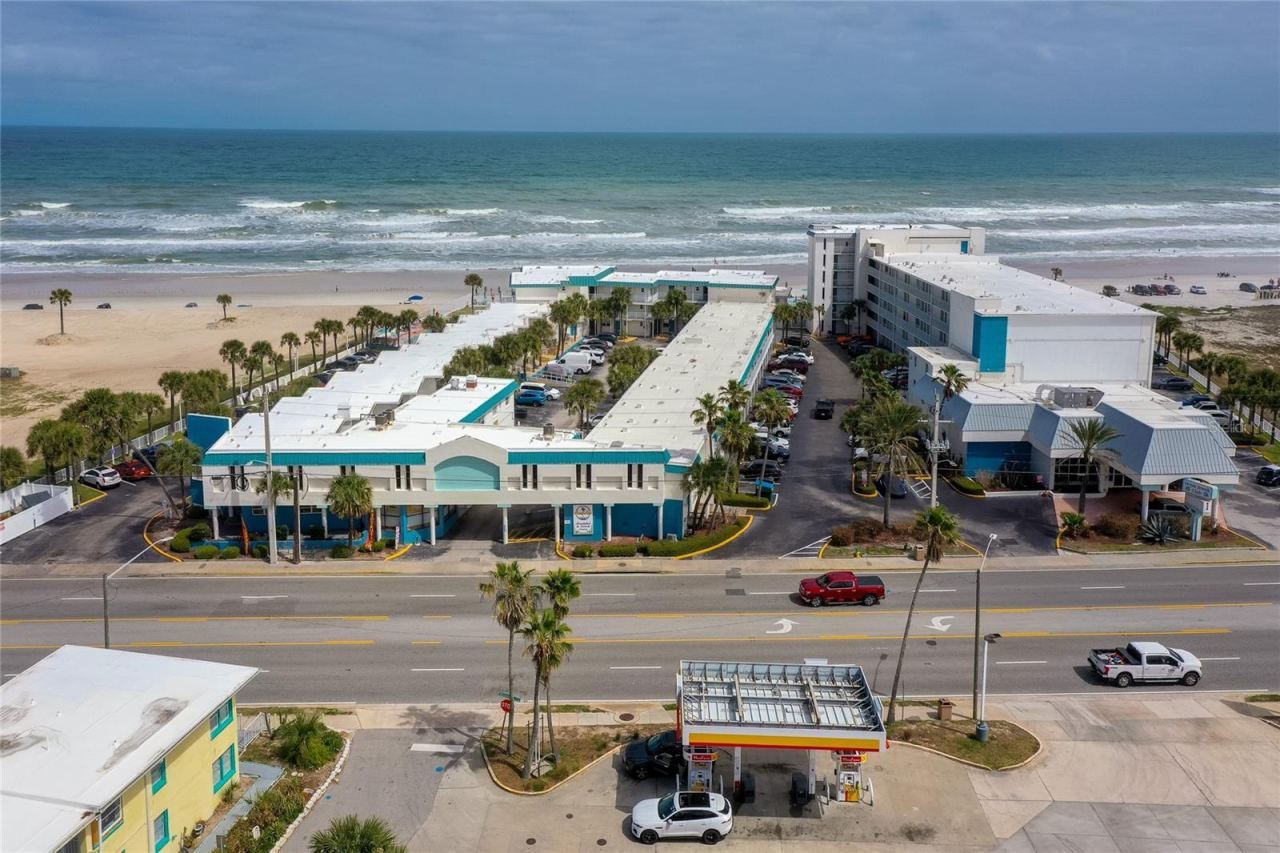 Photo 2 of 20: Oceanfront complex setting with direct beach access and a prime coastal location just steps from the sand. This elevated view highlights the community’s layout, parking, and proximity to the shoreline