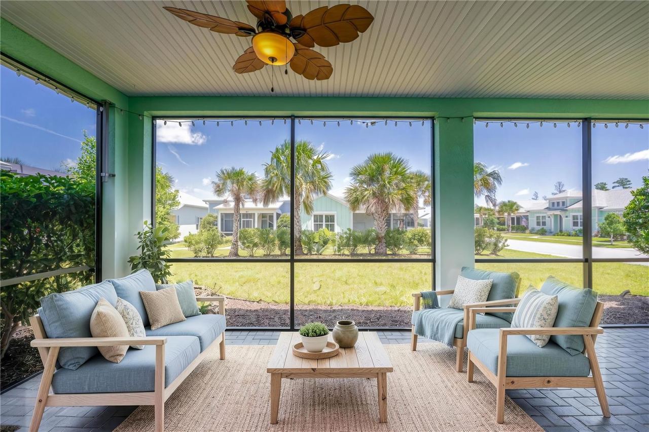 Photo 17 of 20: Virtually Staged - Screened-in back patio paved with brick pavers, featuring a beadboard ceiling with a tropical-leaf ceiling fan and scenic views of the manicured lawn.