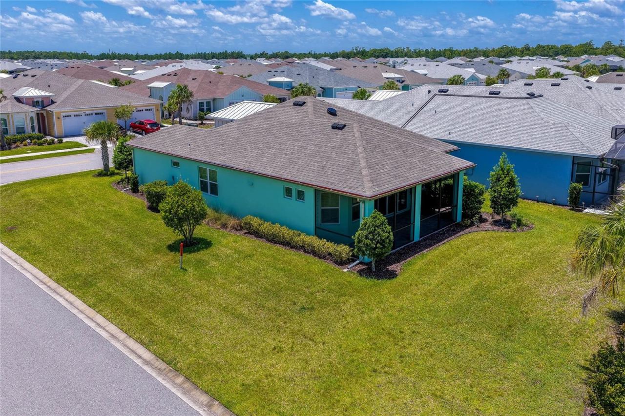 Photo 3 of 20: Elevated side view of the bright mint-green home highlighting its dark shingle roofline, screened-in patio, and manicured green lawn.