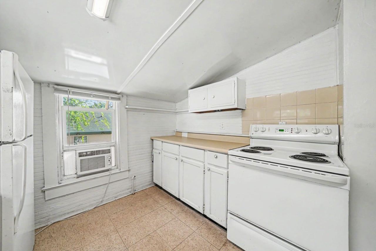 Photo 14 of 20: Bright Kitchen with White Cabinetry, Tile Counters & Windows with Natural Light