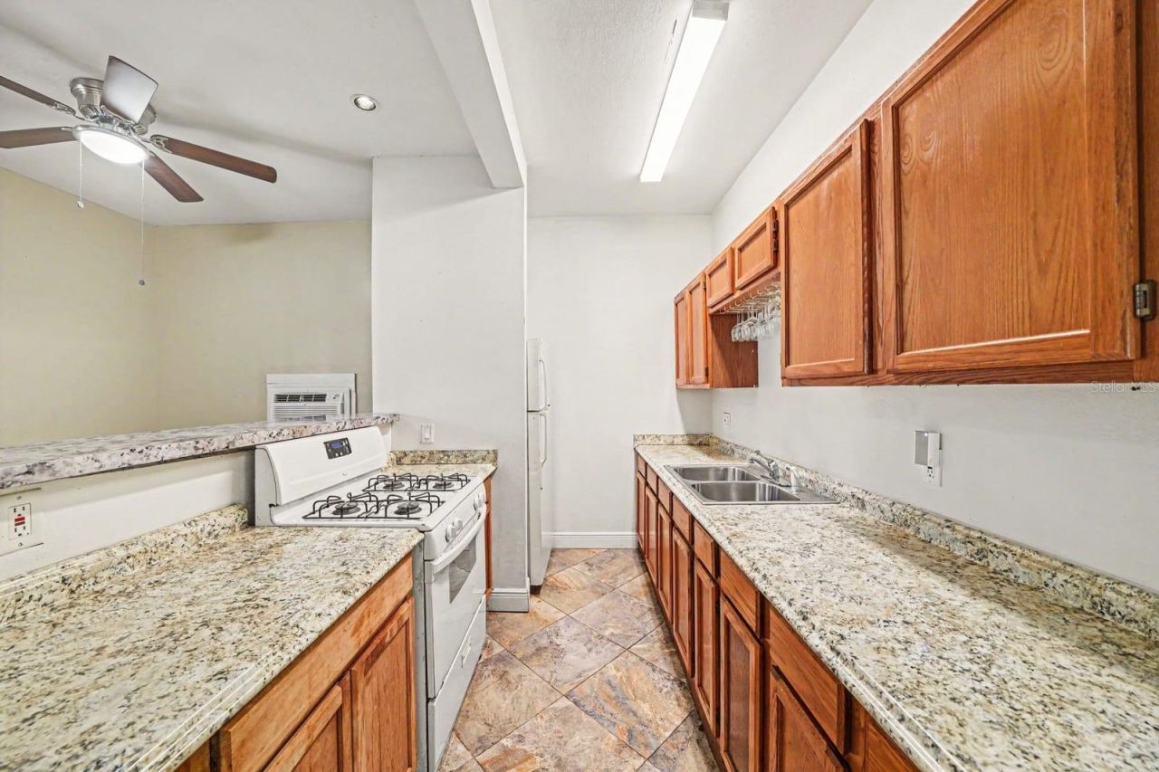 Photo 9 of 20: Galley Kitchen with Wood Cabinetry, Granite Counters & Stainless Steel Appliances