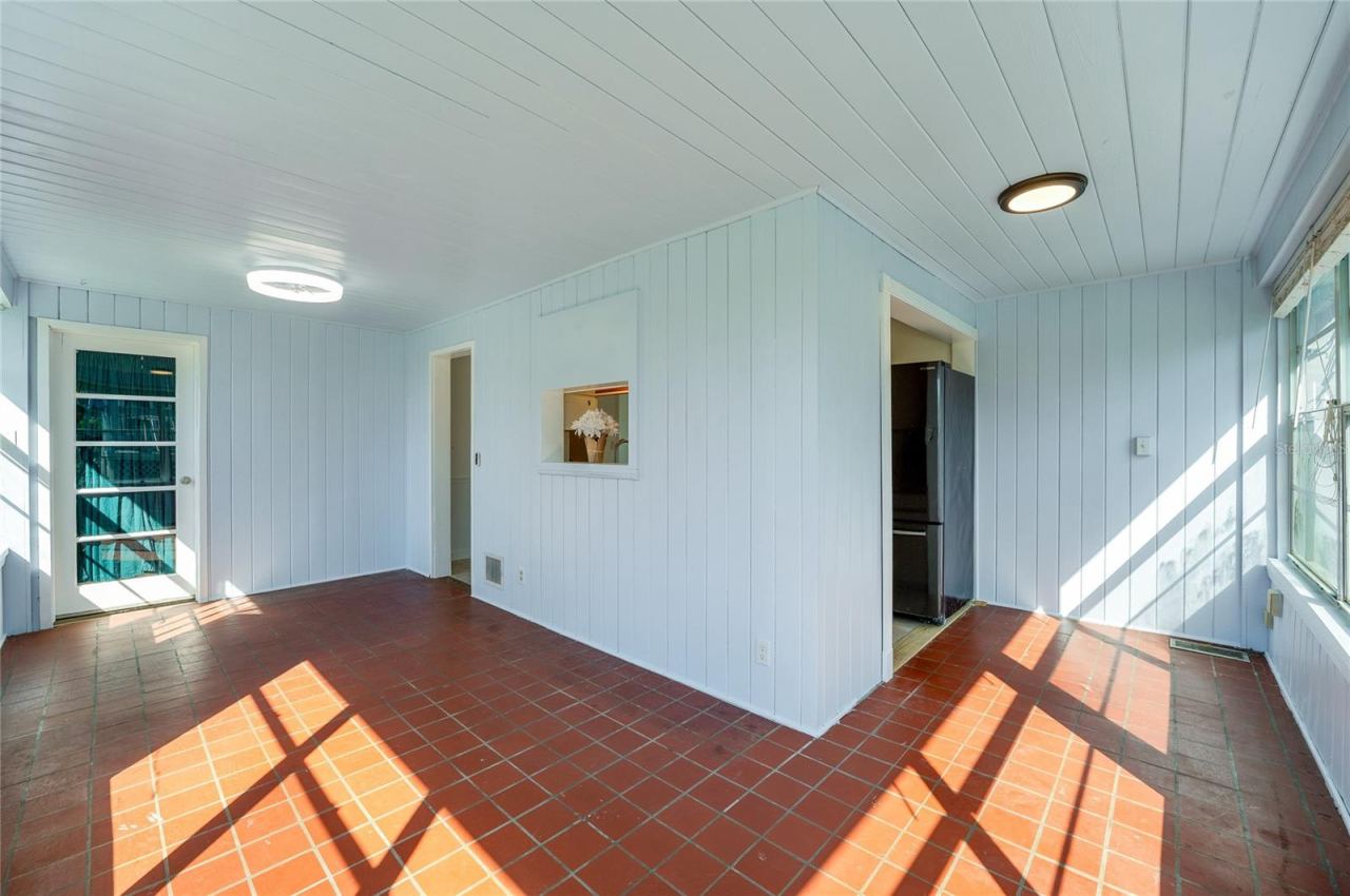 Photo 12 of 20: Sun-filled dining area and breakfast nook showcasing red tile flooring, modern flush-mount lighting, and white paneled walls. Large windows fill the space with natural light while direct door access leads outdoors.