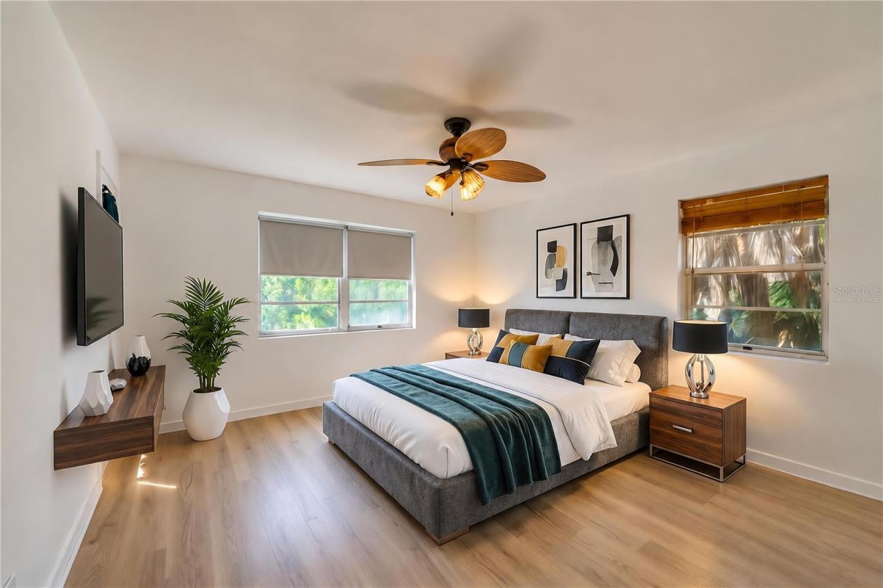 Photo 14 of 20: Virtually Staged - Generous interior room featuring light LVP flooring, crisp white walls, and a woven palm leaf ceiling fan. Multiple windows fill the space with natural light.