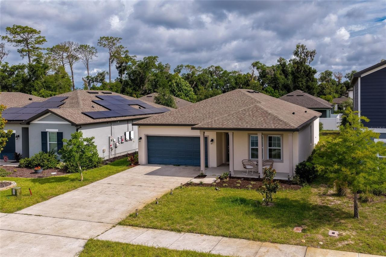 Photo 3 of 20: Angled aerial view highlighting the home’s architectural design, complete with a classic gabled roofline and an expansive front yard. The view also captures neighboring properties, emphasizing the community's clean and cohesive streetscape.