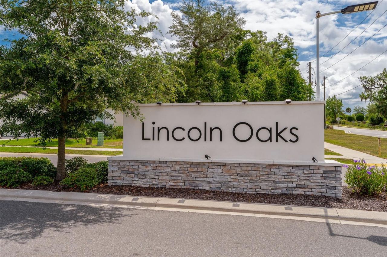 Photo 6 of 20: The stone-accented community monument sign for "Lincoln Oaks," nestled beautifully among mature trees and manicured landscaping alongside the neighborhood roadway.