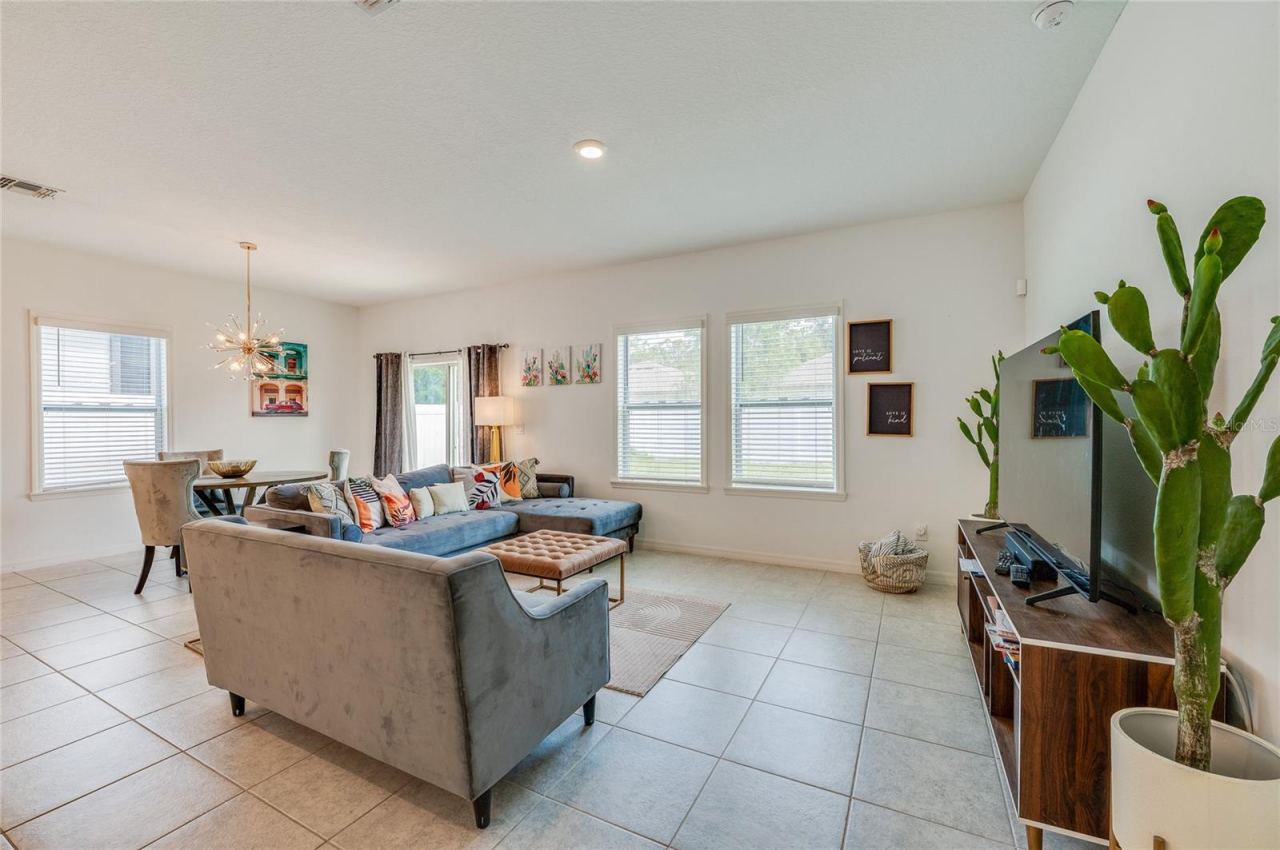 Photo 9 of 20: Spacious living area with large windows that provide abundant natural light and look out toward the backyard. The room features neutral tiled flooring and recessed lighting