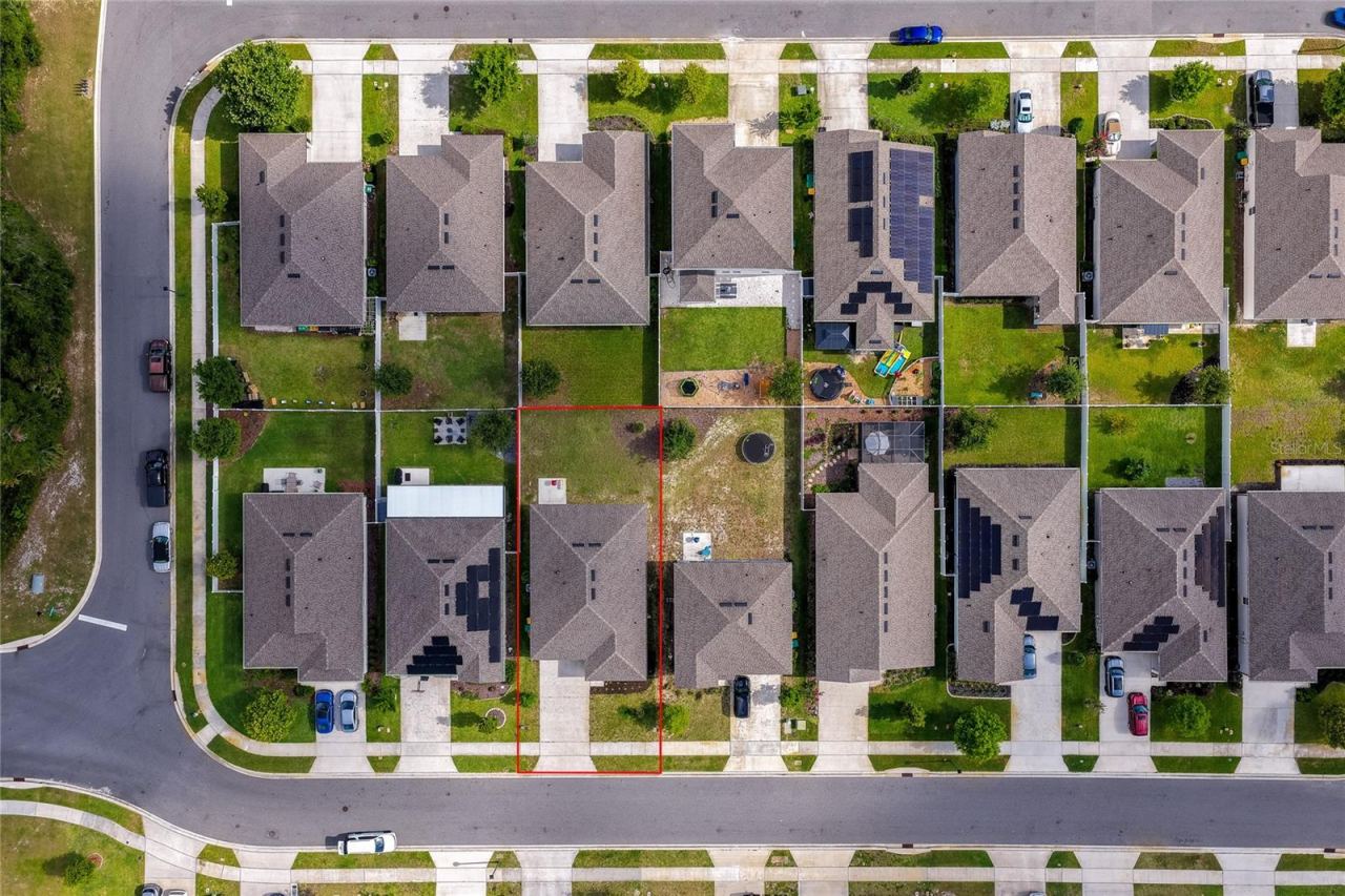 Photo 4 of 20: A birds-eye top-down aerial view detailing the layout of the property, outlined clearly in red to show lot boundaries, roof structure, and driveway alignment. The surrounding suburban grid illustrates the master-planned design of the community.