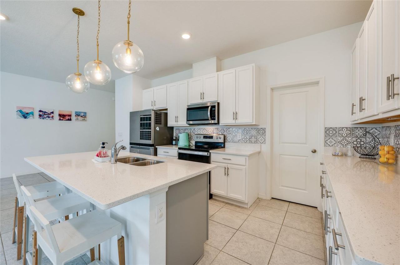 Photo 14 of 20: Alternate angle of the kitchen highlighting the built-in microwave, flat-top range, and a nearby interior door leading to a pantry. The layout provides plenty of counter space for meal preparation.