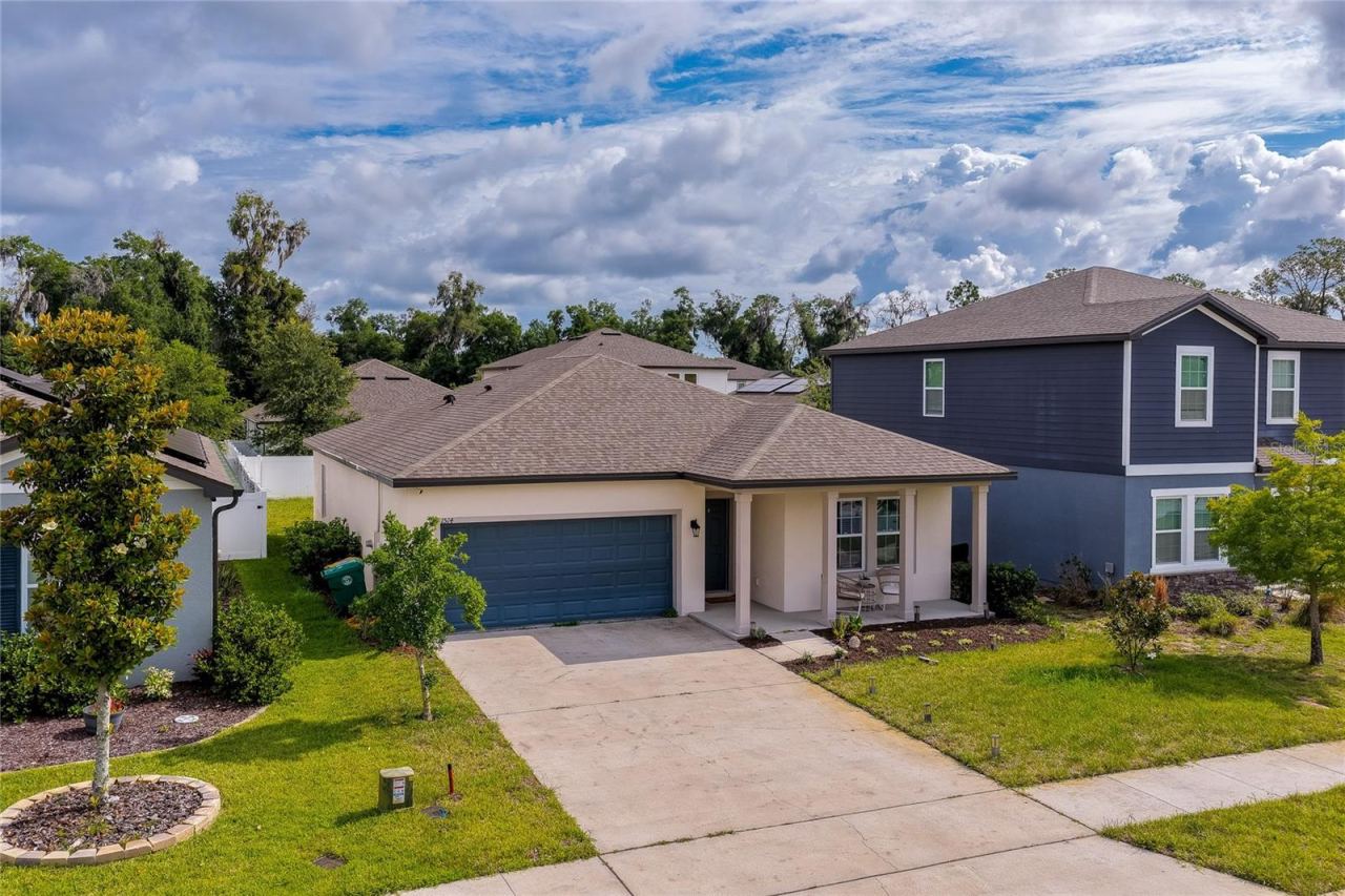 Photo 2 of 20: Elevated perspective of a contemporary single-family home showcasing a pristine concrete driveway, a two-car garage, and a welcoming front porch accent.