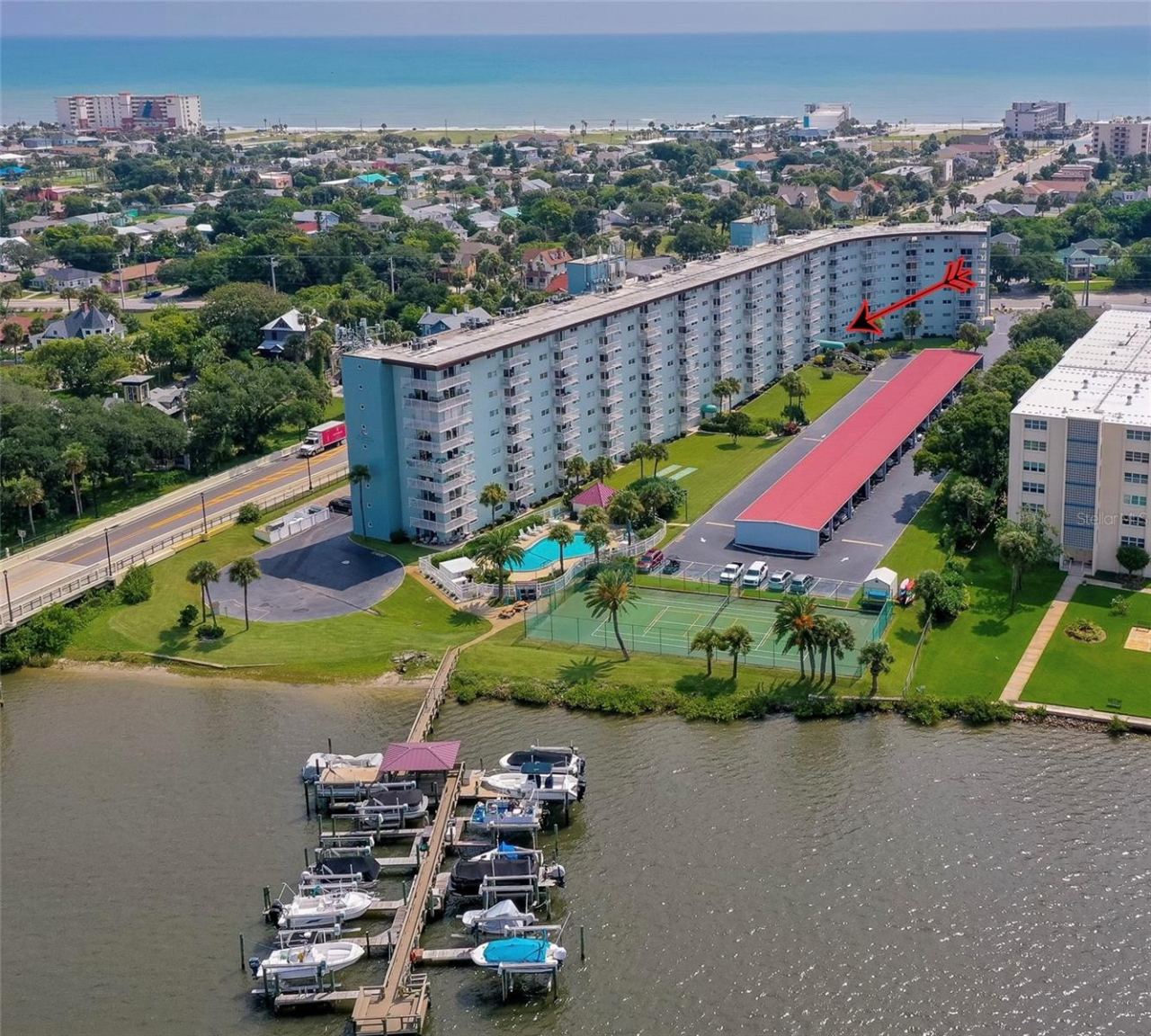 Photo 1 of 20: Elevated perspective showcasing the building’s proximity to the water, nearby beach access, and surrounding neighborhood.
